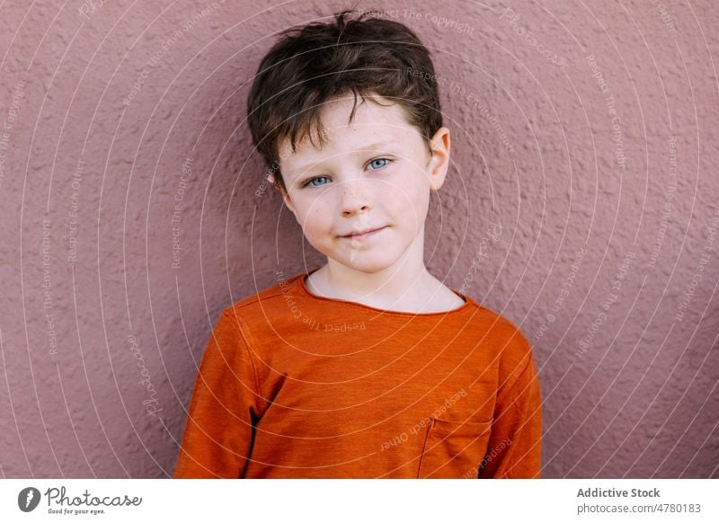 Cute boy standing near wall kid street appearance childhood style casual candid gaze cute dark hair portrait adorable city content glad summertime brunet light