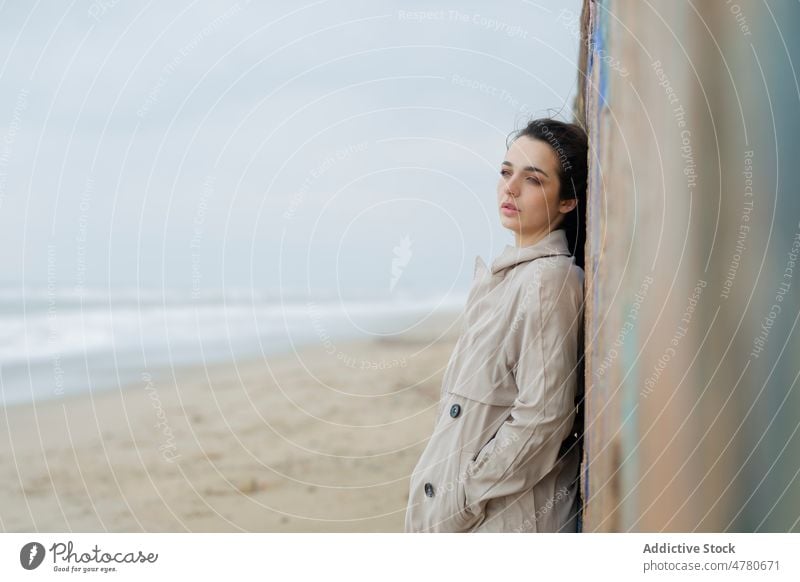 Peaceful woman near wall on shore coast beach water sea seaside coastal feminine dreamy flying hair seashore thoughtful weather lady nature attractive female