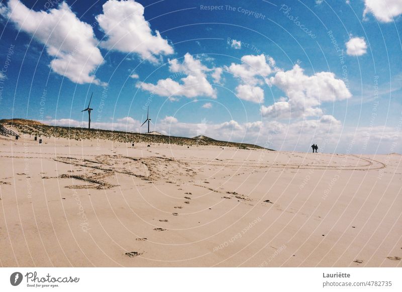 Wind turbines on the beach with a romantic couple in the distance sand landscape desert nature sky windmill plant azure slope desert area landscape - scenery