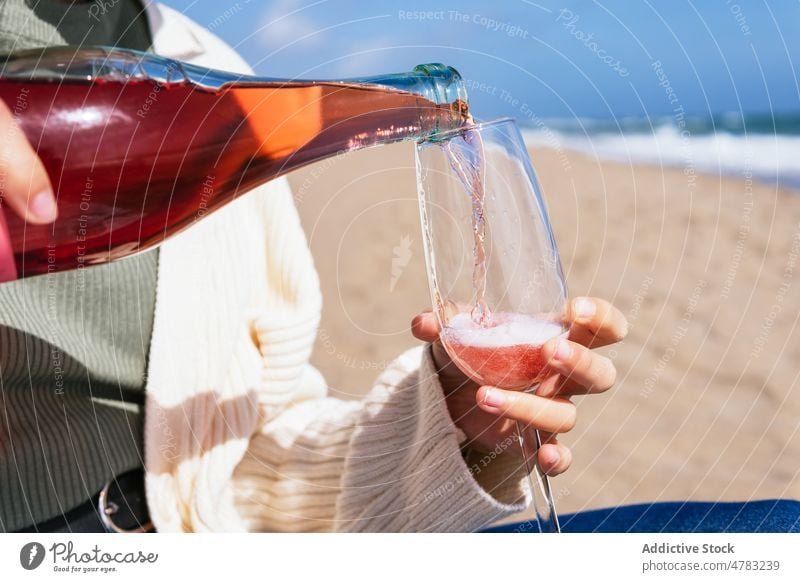 Unrecognizable woman pouring rose champagne on beach sparkle wine glass sea shore female alcohol booze celebrate tropical fizz sand bottle wineglass drink