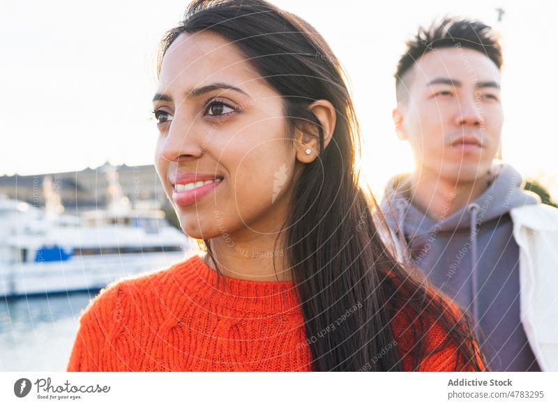 Cheerful multiethnic couple on embankment waterfront port harbor sea spend time bonding pastime relationship love date summer positive optimist street