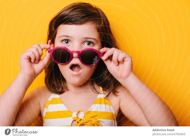 Astonished girl in stylish sunglasses kid style trendy appearance fashion accessory amazed astonish surprise shock disbelief wow childhood light cute studio