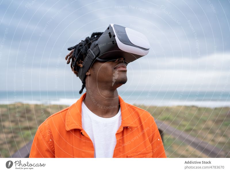 Black man exploring virtual reality on seashore vr cyberspace boardwalk futuristic goggles embankment style glasses waterfront immerse african american black