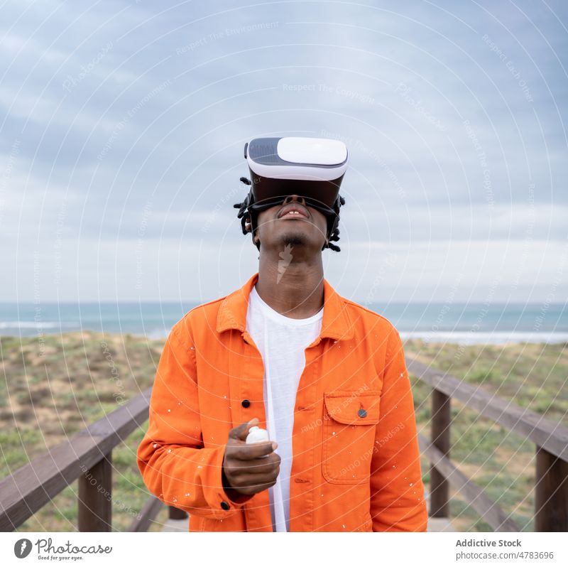 Black man exploring virtual reality on seashore vr cyberspace boardwalk futuristic goggles embankment style glasses waterfront immerse african american black