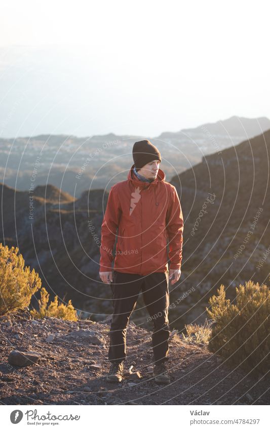 Active and young traveller with a smile on his face enjoys the view from Pico Ruivo, the highest mountain on the Portuguese island of Madeira. Portrait at sunrise in the mountains