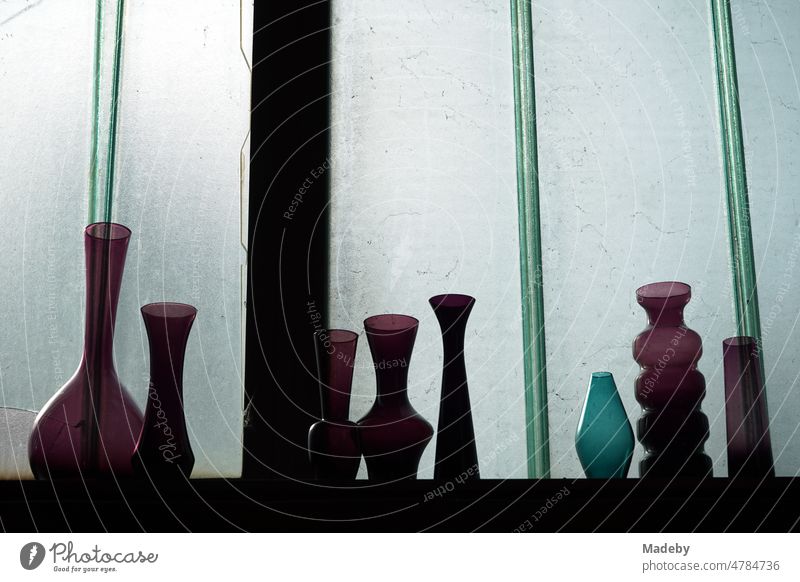 Coloured vases and flasks made of glass on a shelf in front of the window pane of an old factory building in the Margaretenhütte district of Gießen on the Lahn in Hesse