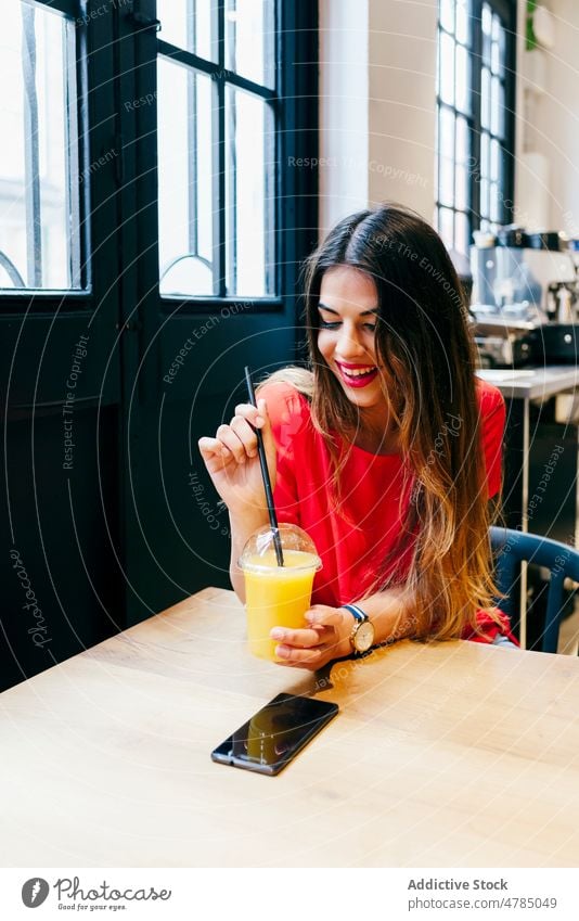 Happy young woman drinking juice in cafe enjoy cup fruit happy joyful vegetarian vegan female fresh detox vitamin meal food natural orange attractive table sit