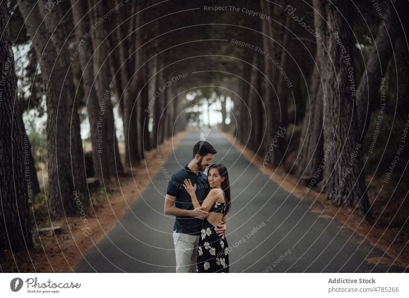 Loving couple embracing on pathway in misty forest alley loving mysterious romantic solitude casual hug road tree asphalt tranquil young adult love travel