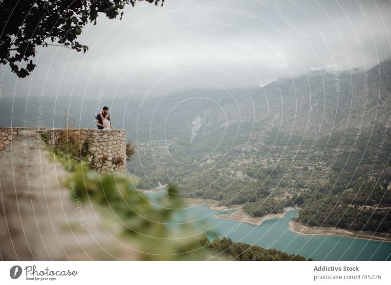 Romantic couple embracing while enjoying countryside view at mountain observation deck travel viewpoint valley scenic landscape love bonding hugging romantic