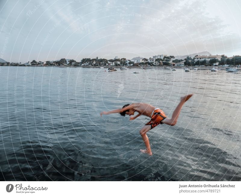 Boy jumping into the sea on a beach in Majorca, Balearic Islands, Spain boy swimming vacation summer teenager splash young child children shore background