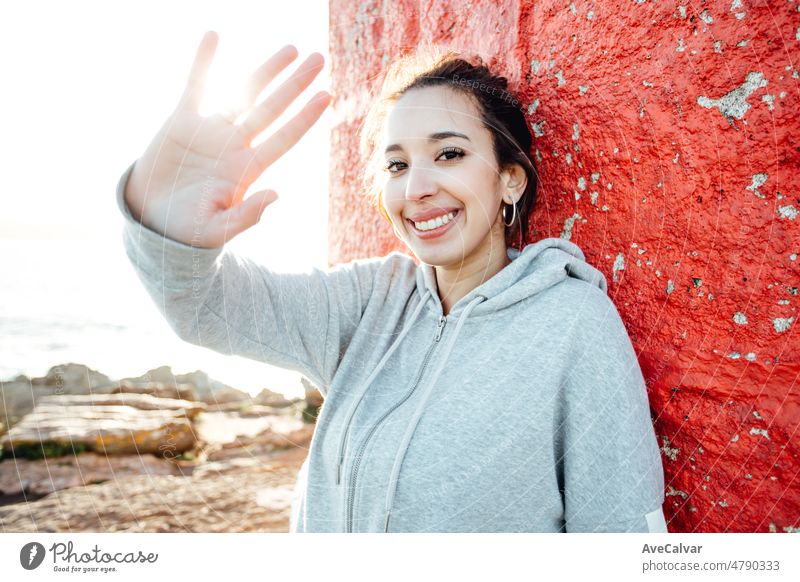 Young woman saluting to camera resting while traveling summer sunny day holiday and vacation concept. Light beam and motion concept. Happy and vibrant life portrait. Traveling alone woman concept.