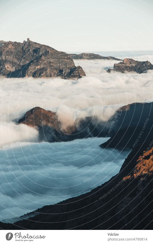 View on highest rocky mountains of the island of Madeira emerge from the clouds into the sunset from the viewpoint of Pico Ruivo do Paul. Beauty of the Portuguese island. Above the clouds