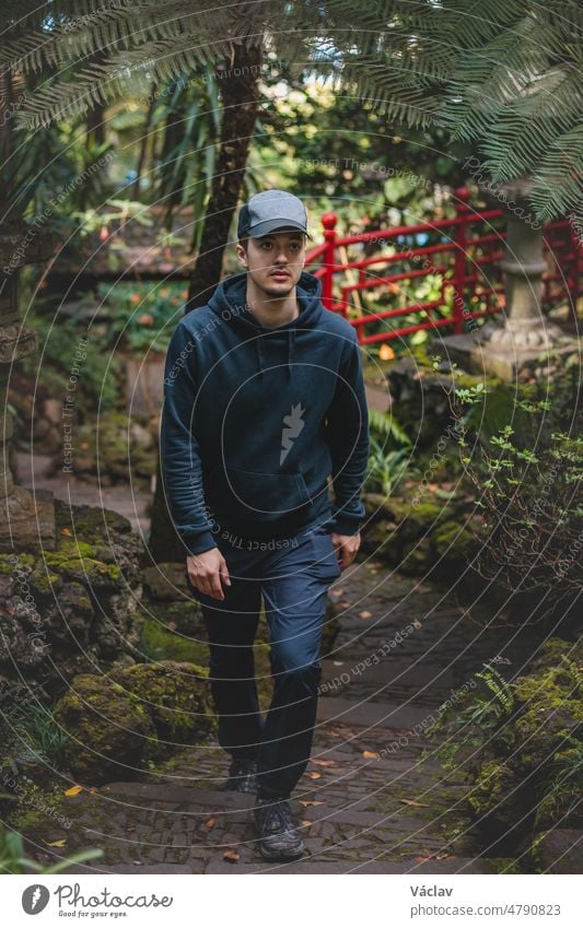 Black-clad adventurer walks through the Monte Palace Madeira botanical garden in Funchal, the capital of the Portuguese island. The beauty of rare plants