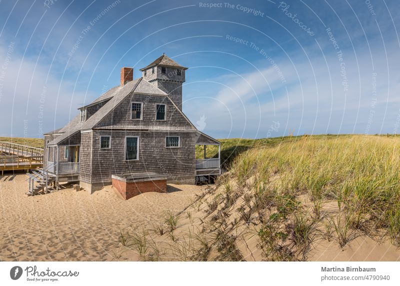 Blue sky and dunes with grass in front of the life saving station building in Provincetown architecture autumn beach blue sky blurred boardwalk cape cape cod