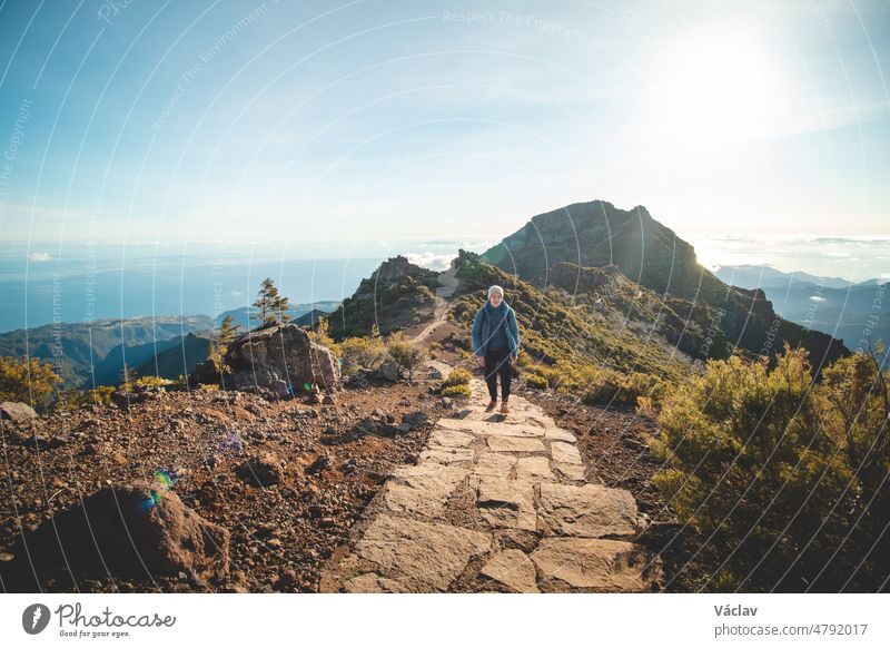 Hiking trail under the Encumeada Baixa mountain with a destination on Madeiras highest mountain, Pico Ruivo. The sun shines on the side of the Madeiran mountain range. Discover portugal island