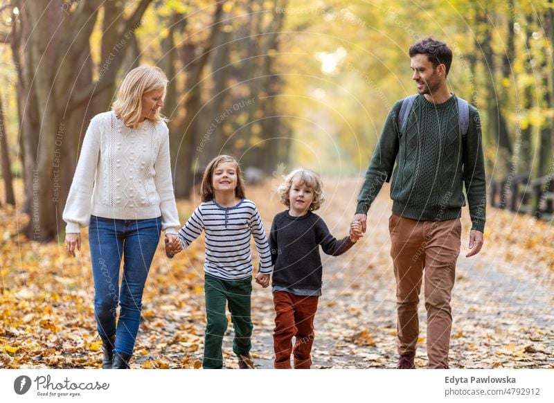 Parents with children on a walk in the park walking running leaf nature field autumn fall man dad father woman female mother family parents relatives son boy