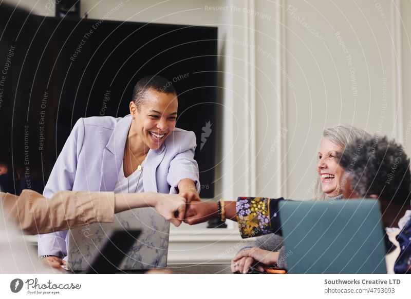 Portrait of cheerful multiracial LGBTQ mid adult woman fist bumping colleagues in meeting and smiling portrait lgbtq fistbump business four smile indoors day