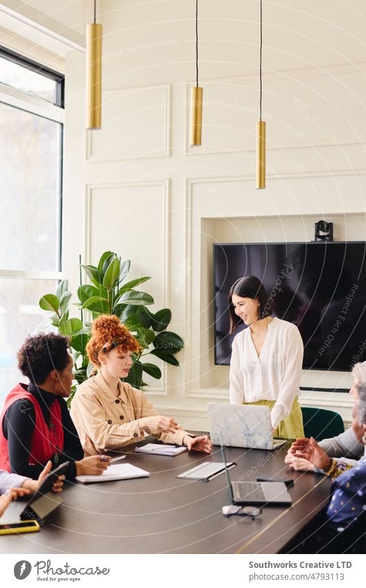 Portrait of Chinese mid adult businesswoman with laptop listening to young white female colleague in boardroom portrait multiethnic meeting smile discuss mature