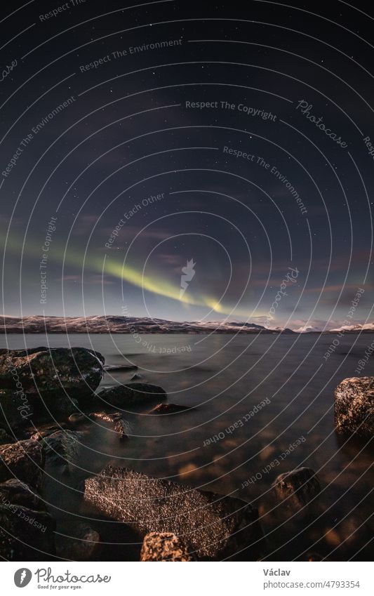 Borealis aurora sweeps over a large lake on a cloudless night in Kilpisjarvi, Lapland, Finland. aurora polaris in green dances across the sky. Scandinavian magic