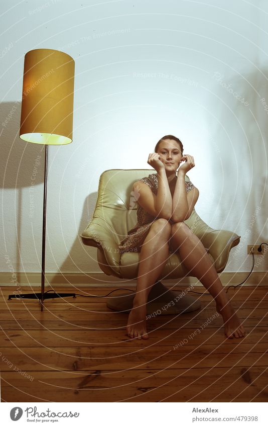 Young woman in dress sitting barefoot on an armchair with her arms to her face Standard lamp Armchair Youth (Young adults) Legs Face Facial expression