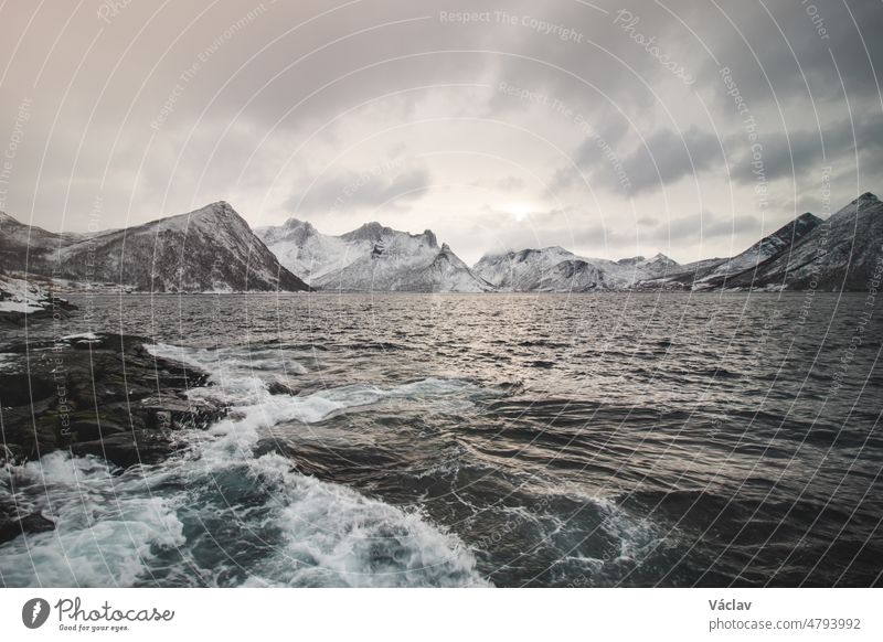 View from the isolated village of Husoy on the island of Senja, Norway. A very lonely fishing village. A view of the stormy Norwegian sea and snow-capped hills beyond the North Pole