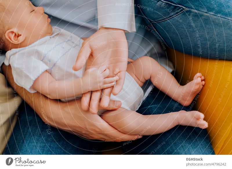 Close up view of a sleepy newborn baby hand and his parents hands close up tiny mother family care child small person holding love protection infant childhood