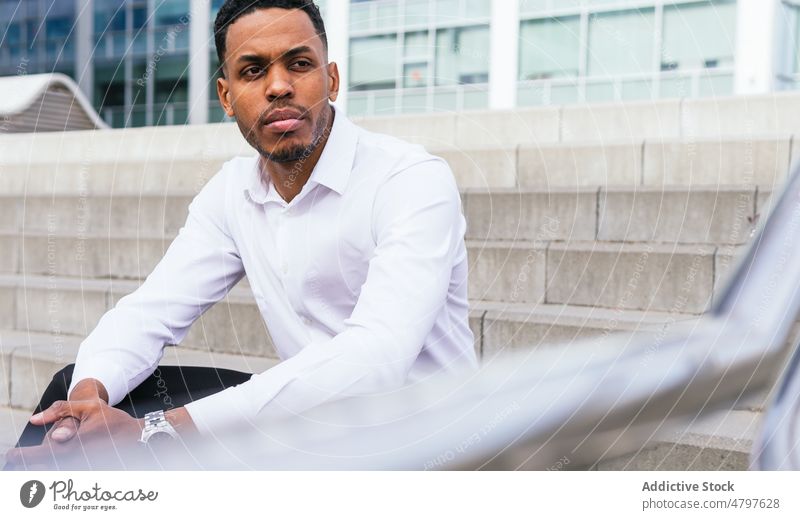 Black businessman sitting on stairs entrepreneur urban city building street formal style modern serious well dressed confident african american black beard