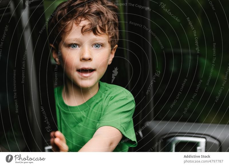 Cute amazed boy in car peek road trip open door smile cute travel portrait curious kid surprise mouth opened astonish journey adventure child vehicle summer