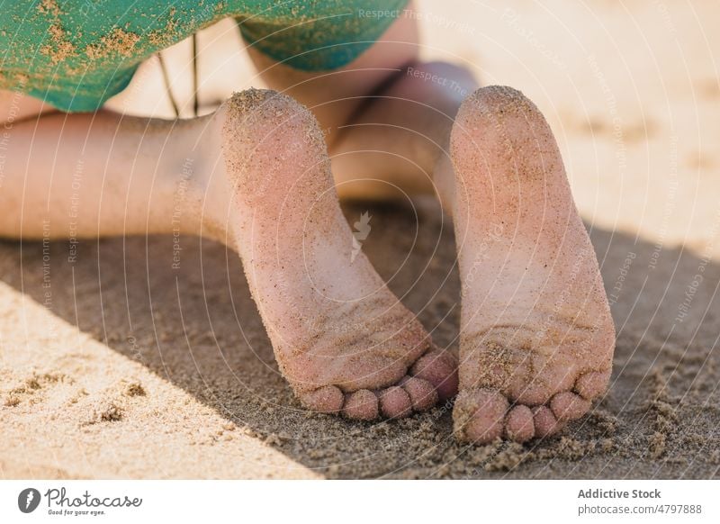 Unrecognizable kid with sandy feet beach summer coast childhood rest shore pastime leisure seashore seacoast resort coastal recreation summertime lifestyle