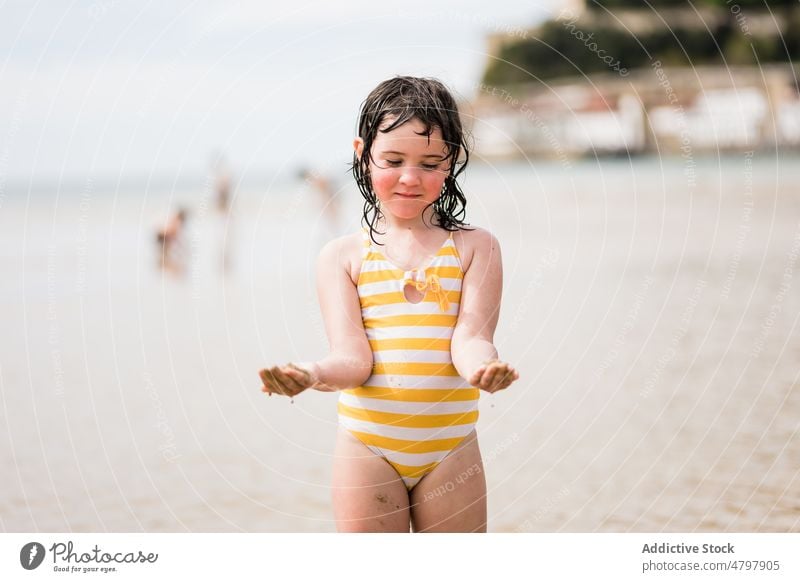 Girl with wet sandy hands on shore kid girl beach summer coast childhood rest playful water recreation leisure cute sea seashore seacoast resort adorable