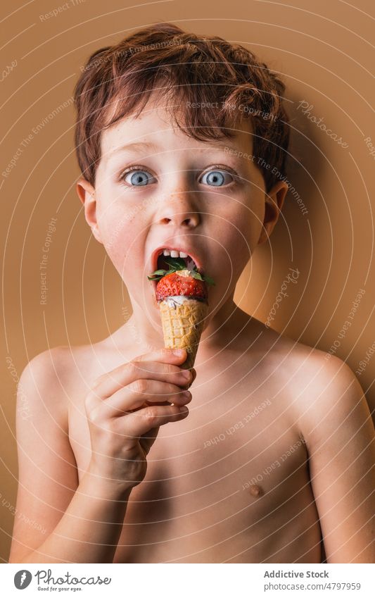 Amazed boy eating ice cream with strawberry carefree astonish sweet dessert cone treat indulge flavor yummy shirtless naked torso amazed surprise cute adorable