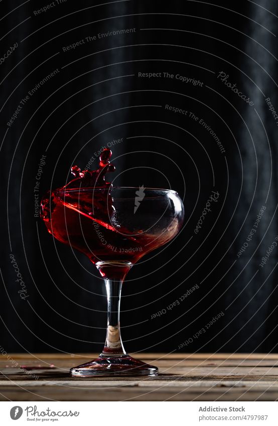 Splashing red wine in wineglass alcohol drink booze splash beverage aperitif flavor spill liquid goblet transparent table crystal taste fragile still life clear