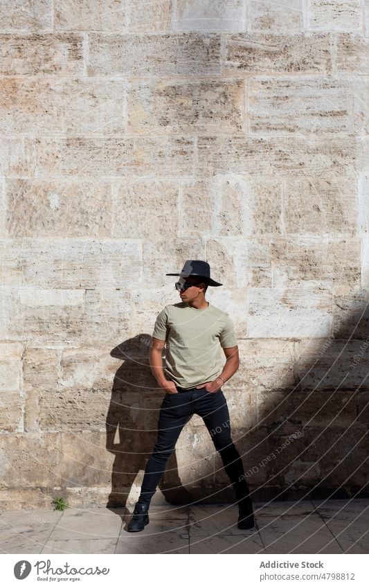 Stylish man near shabby wall street style city urban fashion design hat headwear headdress district building trendy appearance weathered worn out town young