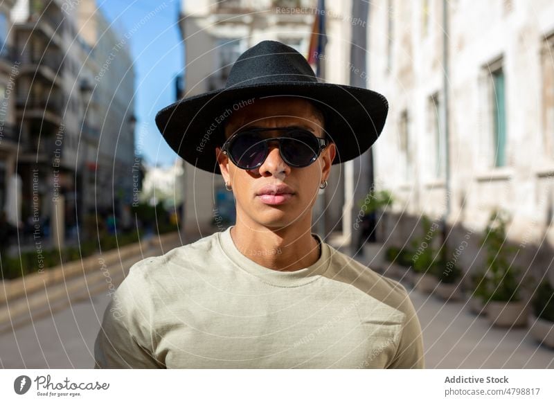 Serious Hispanic man in hat street style city urban fashion design appearance walkway headwear headdress district pathway building house trendy hispanic town