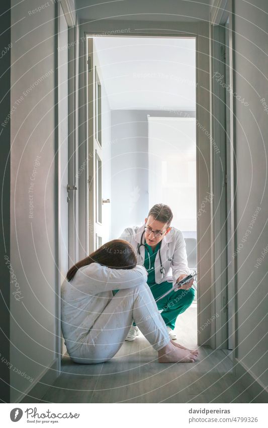 Psychiatrist talking to patient sitting on the floor in a mental health center psychiatrist female woman disorder corridor medical hospital illness therapy