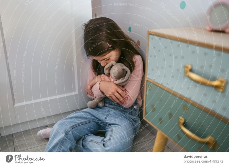 Unhappy girl hugging stuffed toy sitting on the floor unhappy little sad fear mental health depressed mental disorder bedroom mood insecure sadness problem