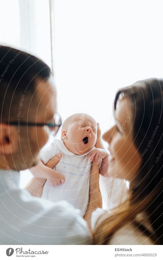 Mom and dad from behind holding their newborn son yawning. New parents mom baby yawing gesturing gesture mother father new parents parenthood motherhood wife