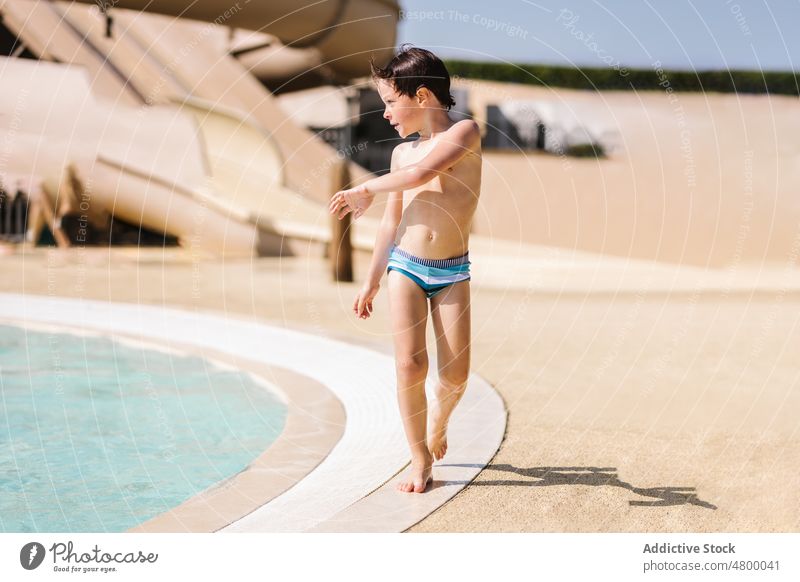 Little boy standing near swimming pool on sunny day poolside ready prepare summer vacation weekend child active holiday resort shirtless swimwear enjoy kid