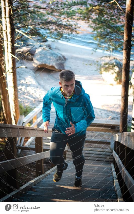 athlete in his training runs up the stairs for better fitness. A 20-year-old athlete in a blue jacket in summer training. Sotkamo, Finland. Active lifestyle