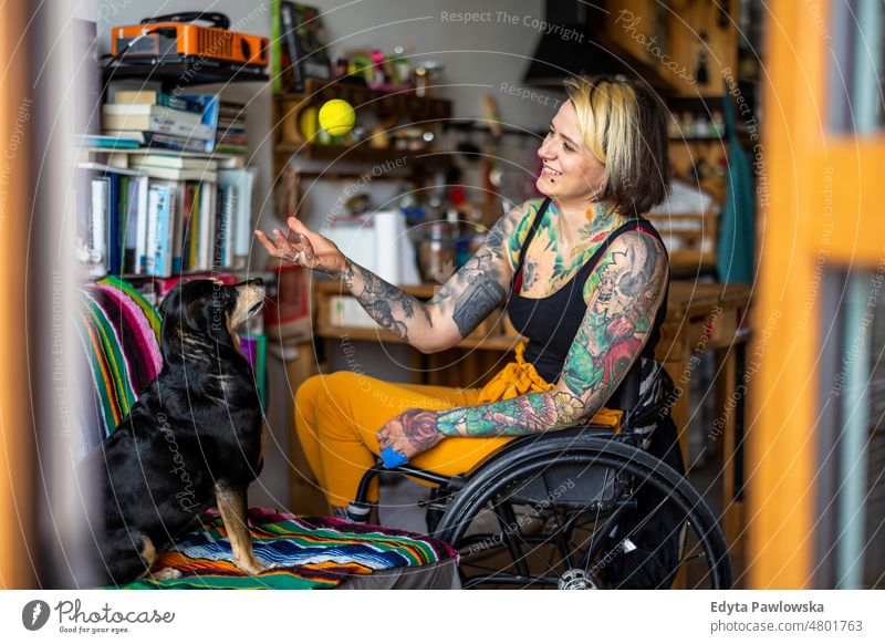 Young woman with disability with her dog at home wheelchair domestic life confidence indoors house people young adult casual female Caucasian attractive