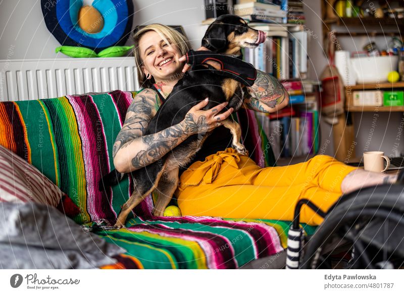 Young woman with disability with her dog at home wheelchair domestic life confidence indoors house people young adult casual female Caucasian attractive