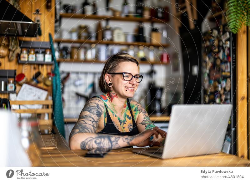 Tattooed woman working on laptop at home domestic life confidence indoors house people young adult casual female Caucasian attractive beautiful mobility tattoos