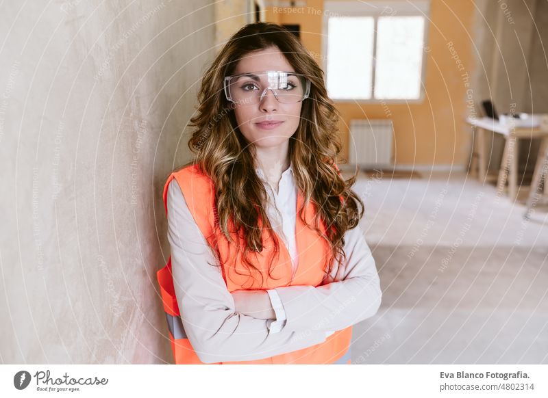 professional confident architect woman in construction site. Home renovation portrait blueprints workspace protective helmet protective jacket mobile phone