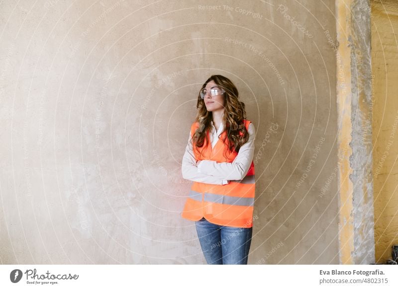 professional confident architect woman in construction site. Home renovation portrait blueprints workspace protective helmet protective jacket mobile phone