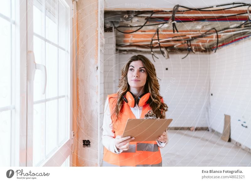 inspector or architect professional woman checking kitchen at construction site. Home improvement home laptop unrecognizable mobile phone blueprints workspace