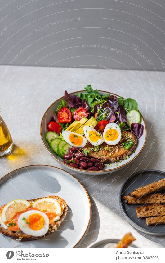 Toast with salmon and medium boiled eggs soft-boiled diet bread yolk yellow toast green salad leaves avocado cherry tomatoes cucumber red beans micro greens