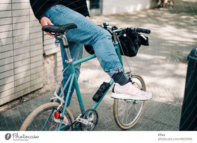 [hansa BER 2022] Man in jeans gets on his hip little blue city bike Bicycle Blue Go up Small Hipster sneakers White sunny urban Lifestyle Retro Easygoing