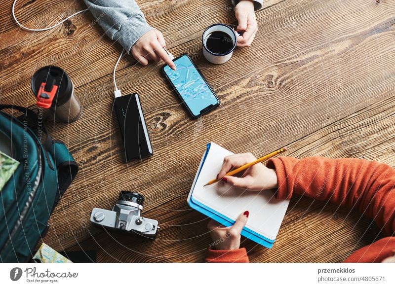 Family planning vacation trip. Girl searching travel destination and routes using navigation map on mobile phone. Charging smartphone with power bank. Using technology while travelling