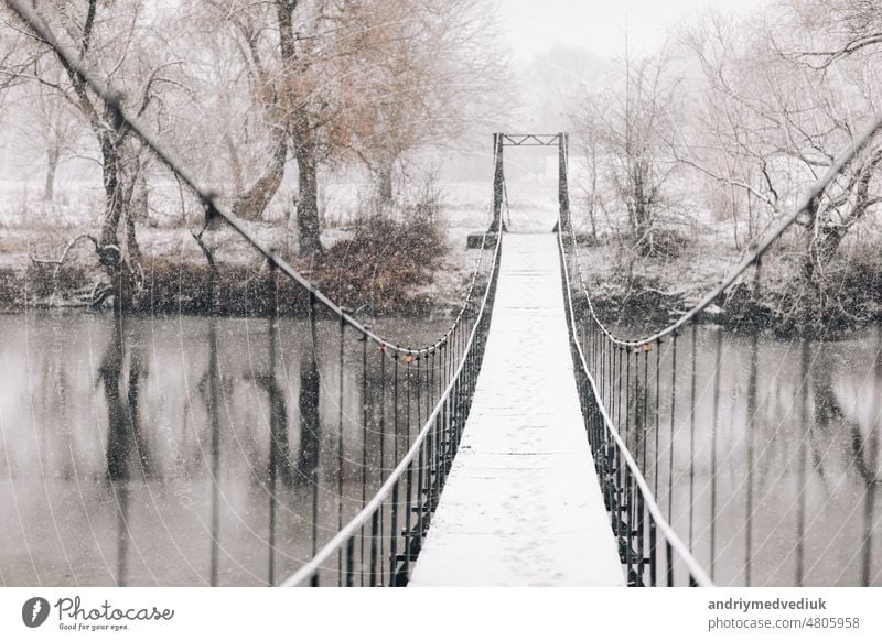 Pedestrian suspension bridge made of steel and wood across the river, winter landscape path hanging forest footbridge travel nature view wooden suspended park