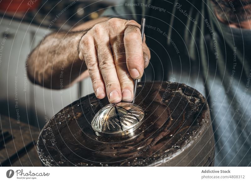 Anonymous silversmith punching ornament on silver lid man carve hammer table workshop male mature middle age create artisan hit handmade skill manufacture